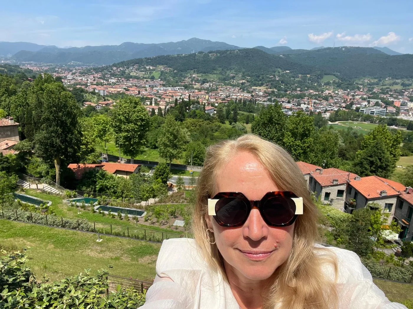 Maria Baumgartner vor einer weiten grünen Landschaft mit Hügeln und Stadtblick.
