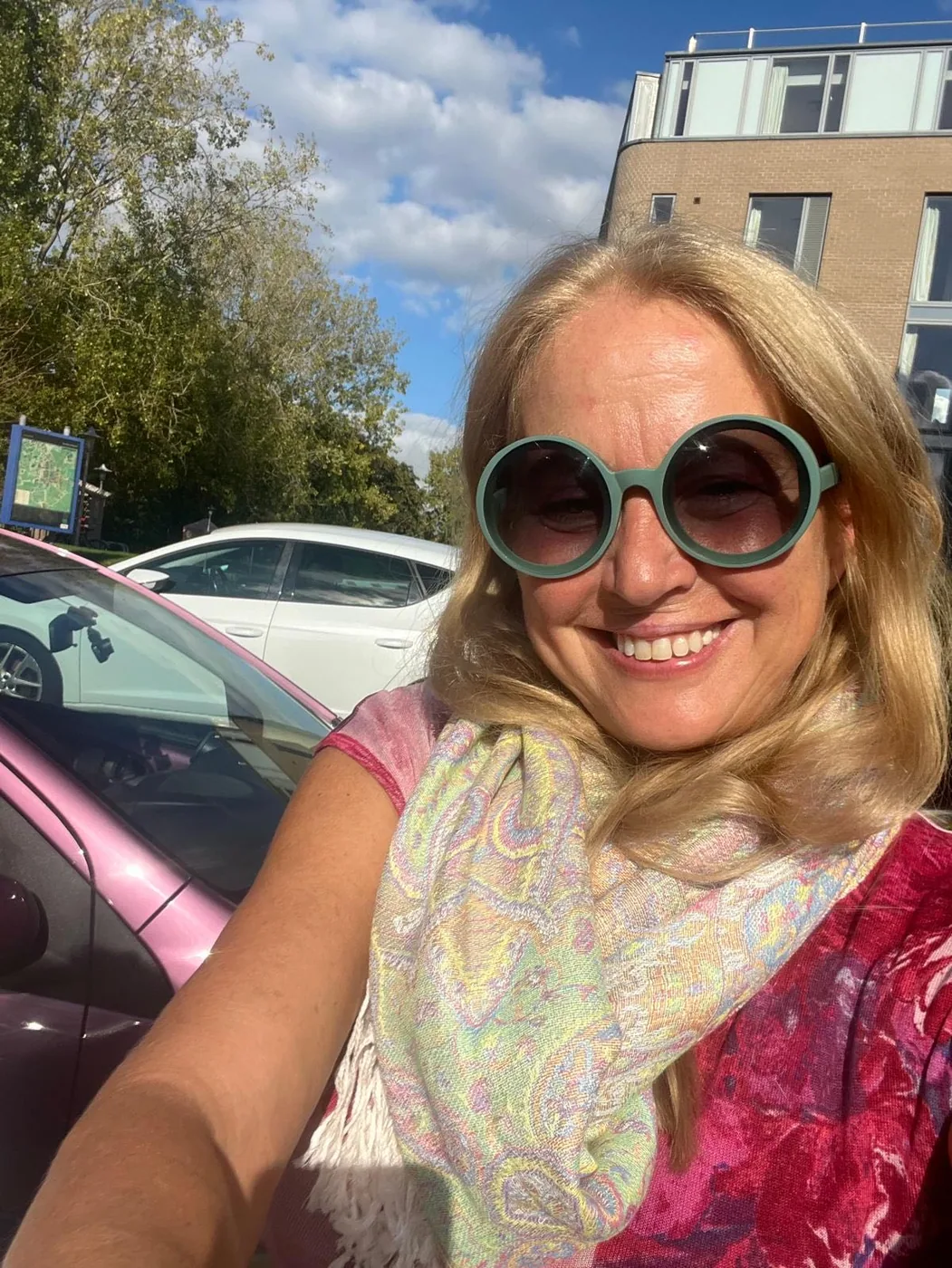Maria mit farbigem Schal und Sonnenbrille draußen.